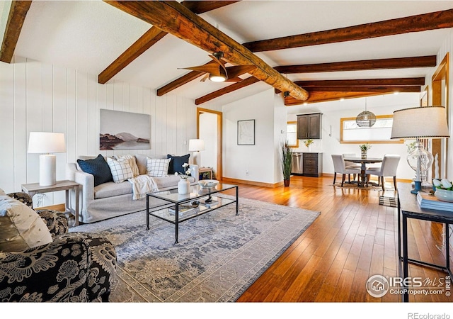 living room featuring ceiling fan, vaulted ceiling with beams, and hardwood / wood-style floors