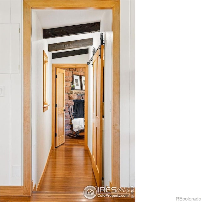 corridor featuring light wood-style floors and beamed ceiling