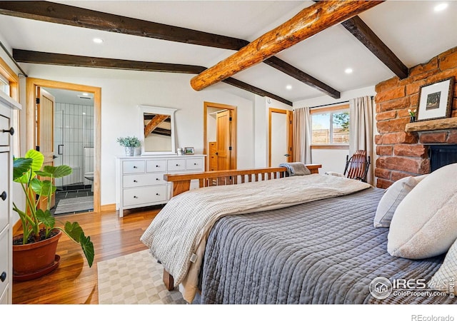 bedroom featuring recessed lighting, beamed ceiling, wood finished floors, and a fireplace