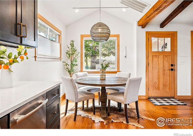 dining space with baseboards, vaulted ceiling with beams, light wood finished floors, and visible vents