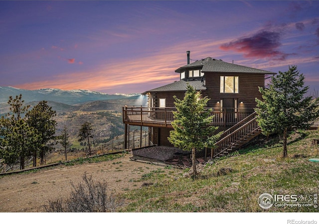 rear view of property with stairs, roof with shingles, and a deck with mountain view