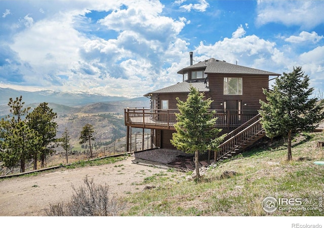 back of house featuring stairs, a deck with mountain view, and driveway