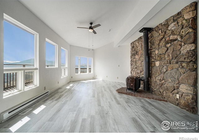 unfurnished living room featuring a ceiling fan, a baseboard heating unit, wood finished floors, and a wood stove