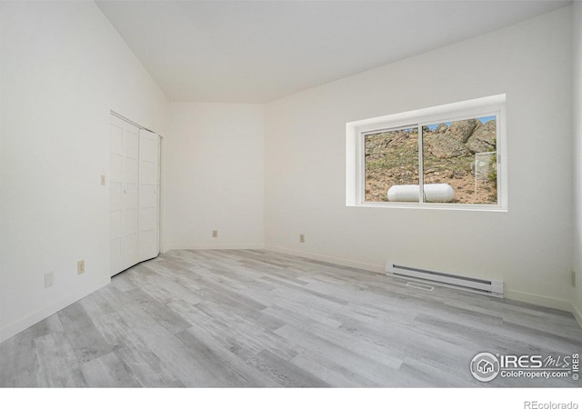 empty room with baseboard heating and light wood-type flooring