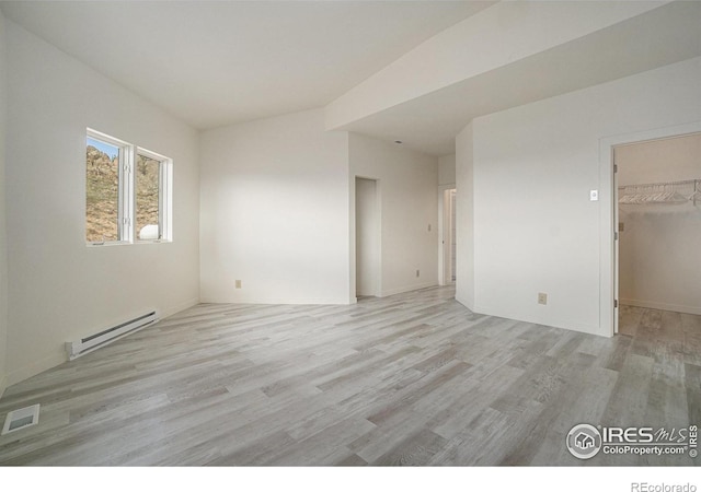 unfurnished room with visible vents, a baseboard radiator, and light wood finished floors