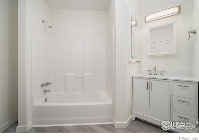 full bathroom with baseboards, washtub / shower combination, vanity, and wood finished floors