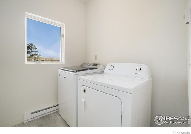 laundry area with laundry area, a baseboard radiator, washer and clothes dryer, and light wood-type flooring