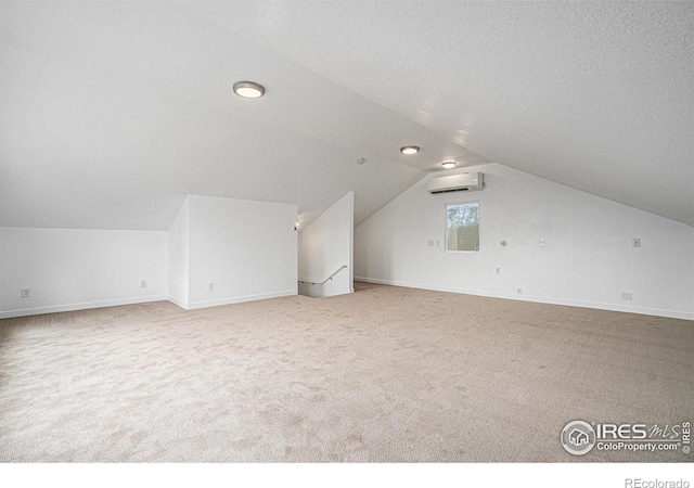 additional living space featuring baseboards, a wall mounted air conditioner, carpet flooring, and vaulted ceiling