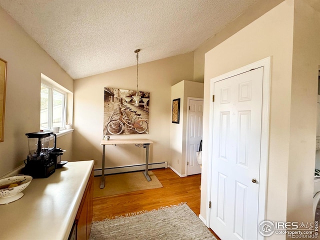 corridor featuring baseboard heating, light wood-type flooring, a textured ceiling, and lofted ceiling