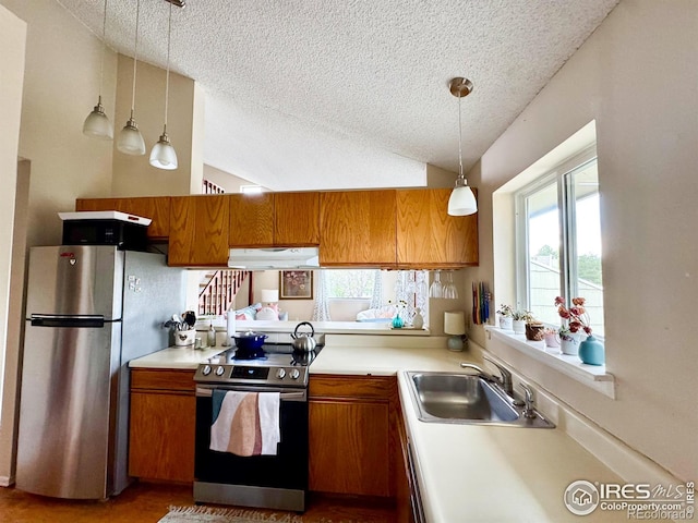 kitchen with brown cabinetry, a textured ceiling, and stainless steel appliances