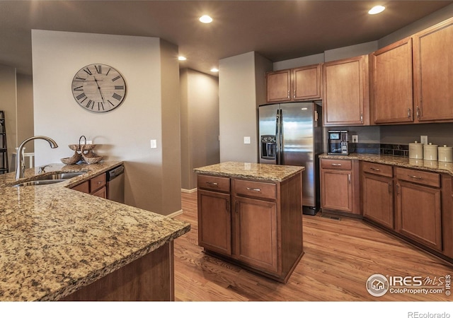 kitchen featuring a center island, appliances with stainless steel finishes, a sink, and light wood-style floors