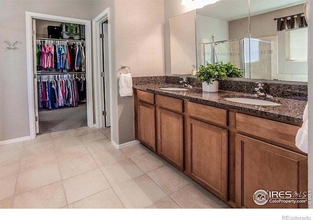 full bath featuring double vanity, baseboards, a shower stall, and a sink
