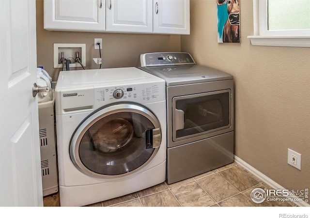 laundry area featuring baseboards, cabinet space, and washing machine and clothes dryer