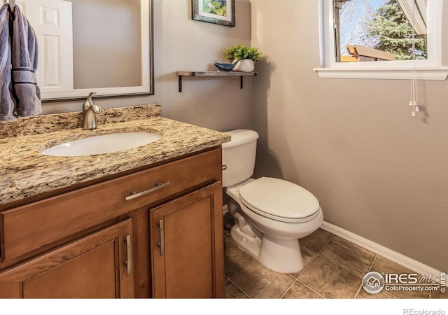 half bathroom with baseboards, tile patterned flooring, toilet, and vanity