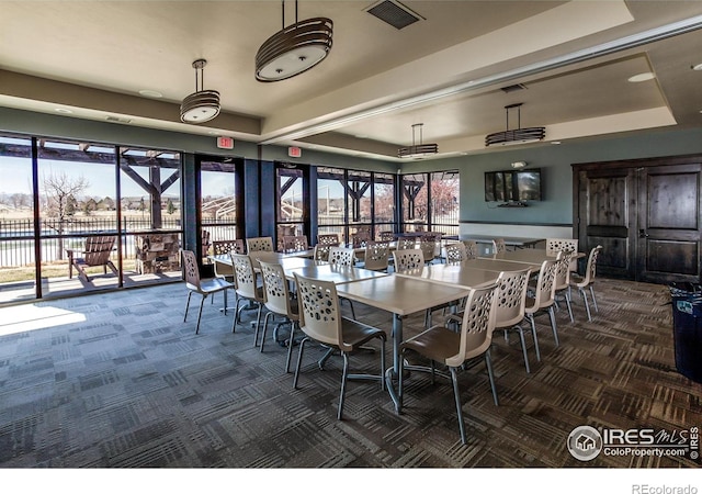 dining space with visible vents, carpet, a water view, and a tray ceiling