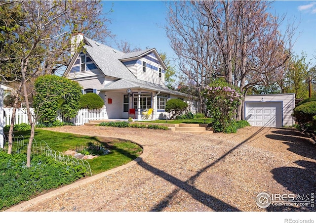 view of front of house featuring fence, driveway, a detached garage, and covered porch