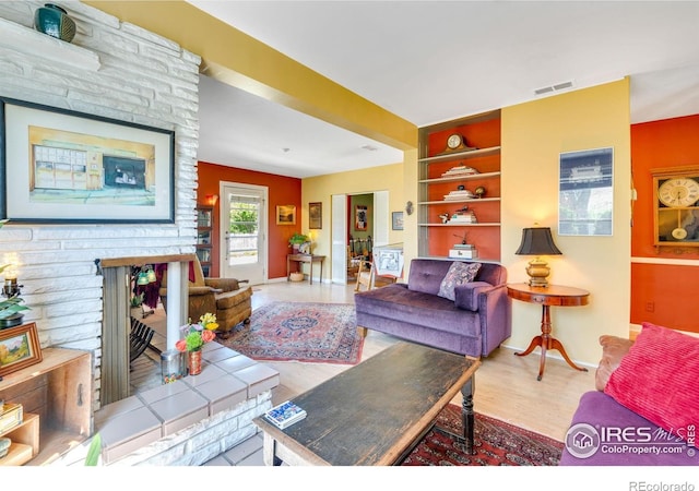 living room featuring visible vents, baseboards, wood finished floors, and built in shelves