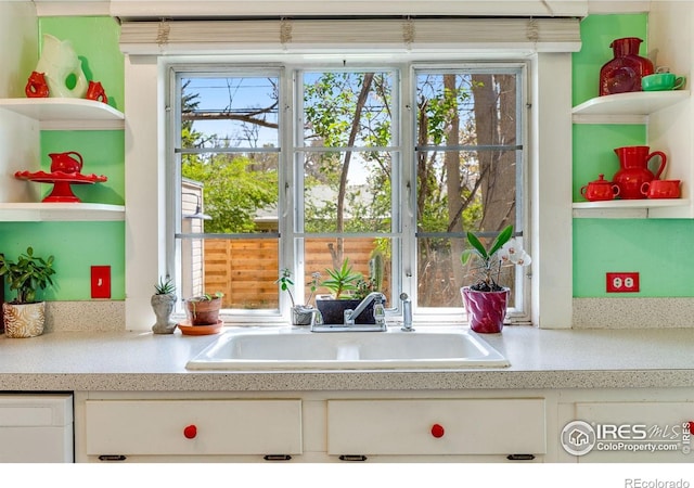 interior details with open shelves, a sink, white cabinets, and light countertops