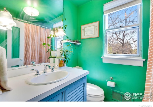 bathroom featuring vanity, a shower with shower curtain, toilet, and visible vents