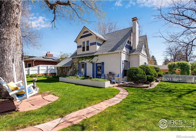 back of property with a yard, brick siding, fence, and a chimney