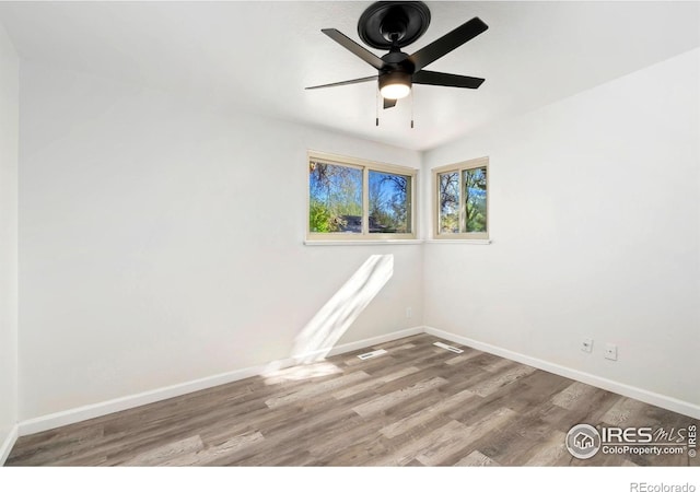 unfurnished room with baseboards, ceiling fan, wood finished floors, and visible vents