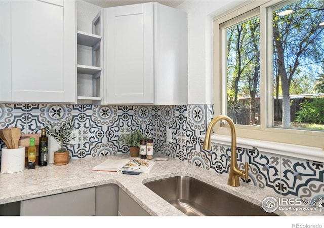 kitchen featuring a sink, open shelves, backsplash, and white cabinets