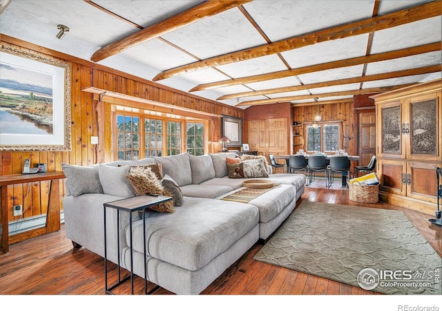 living room with wood walls, healthy amount of natural light, a baseboard heating unit, hardwood / wood-style floors, and beamed ceiling