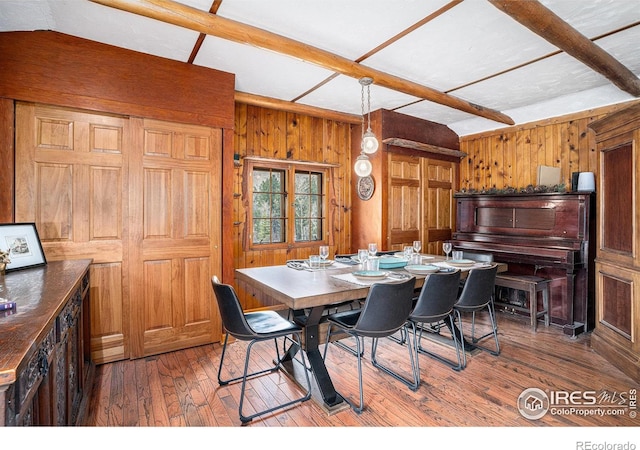 dining space featuring wood walls, beam ceiling, and hardwood / wood-style floors