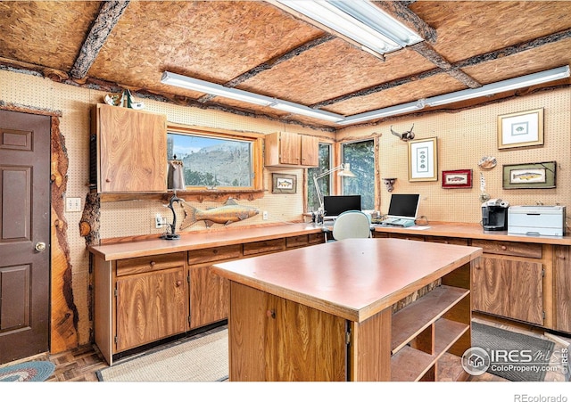 kitchen with light countertops, brown cabinets, an office area, and open shelves