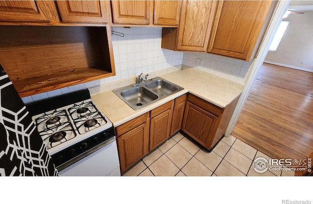 401 Park St, Sterling, CO 80751 - kitchen with gas range gas stove, light countertops, brown cabinets, a sink, and backsplash