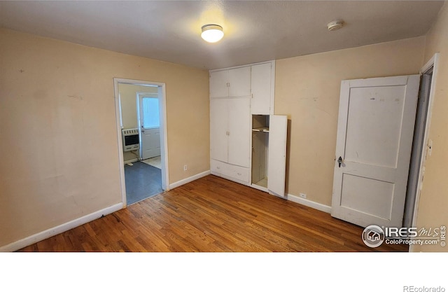 401 Park St, Sterling, CO 80751 - unfurnished bedroom featuring baseboards, heating unit, wood finished floors, and a closet