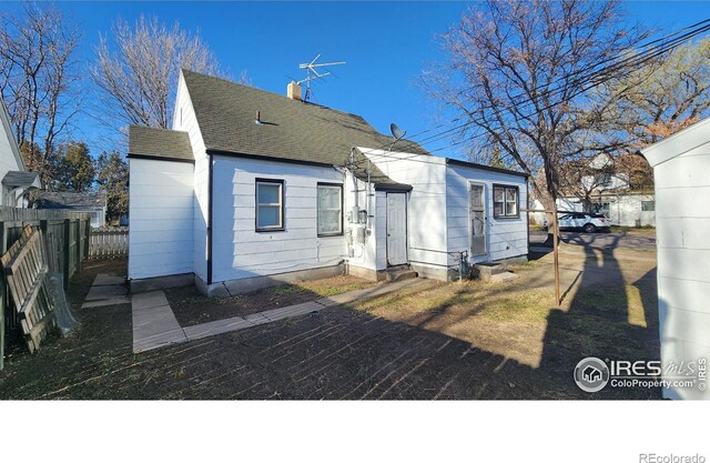401 Park St, Sterling, CO 80751 - back of property featuring a shingled roof, fence, and a chimney
