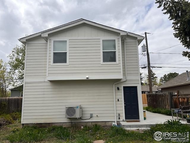 rear view of property with board and batten siding, fence, ac unit, and a patio area