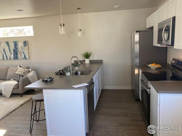 kitchen with a peninsula, open floor plan, a kitchen breakfast bar, a sink, and stainless steel appliances