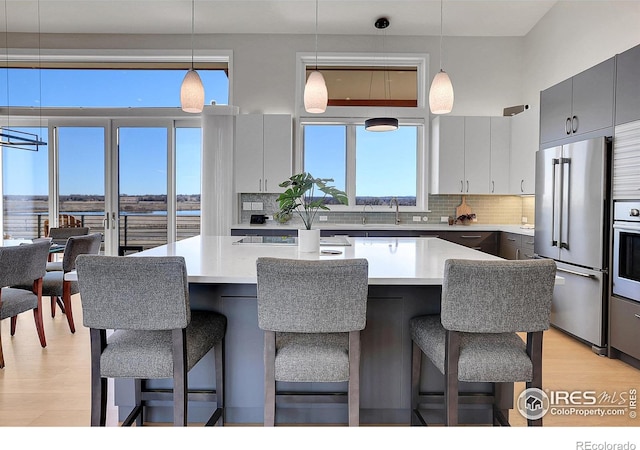 11251 Lookout Dr, Longmont, CO 80504 - kitchen featuring appliances with stainless steel finishes, a kitchen bar, tasteful backsplash, and light wood finished floors