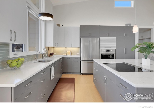 11251 Lookout Dr, Longmont, CO 80504 - kitchen featuring appliances with stainless steel finishes, gray cabinetry, a sink, pendant lighting, and tasteful backsplash