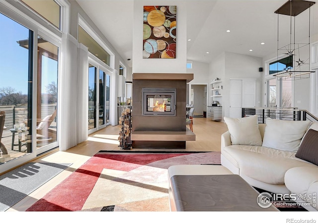 11251 Lookout Dr, Longmont, CO 80504 - living area with a towering ceiling, wood finished floors, a multi sided fireplace, recessed lighting, and a chandelier