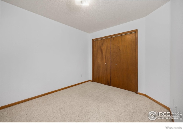 1231 W Swallow Rd Unit 314, Fort Collins, CO 80526 - unfurnished bedroom with baseboards, a textured ceiling, carpet, and a closet