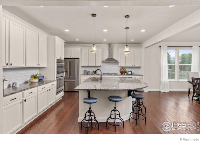 5845 Shadow Creek Ct, Windsor, CO 80528 - kitchen with wall chimney range hood, appliances with stainless steel finishes, a sink, dark wood-style floors, and recessed lighting