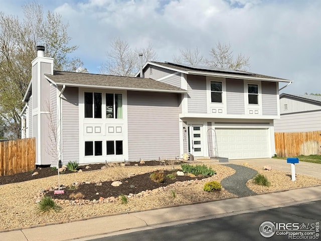 16807 E Napa Dr, Aurora, CO 80013 - view of front of house featuring an attached garage, fence, a chimney, and concrete driveway