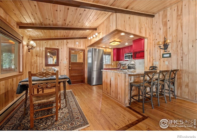565 Hemlock Dr, Lyons, CO 80540 - kitchen with beamed ceiling, wood walls, appliances with stainless steel finishes, and light wood-style floors