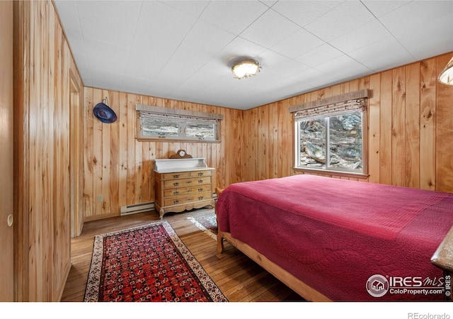 565 Hemlock Dr, Lyons, CO 80540 - bedroom featuring wooden walls, a baseboard radiator, and wood-type flooring