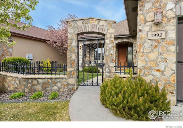1992 Vineyard Dr, Windsor, CO 80550 - doorway to property with fence, a gate, and stone siding