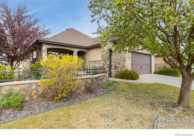 1992 Vineyard Dr, Windsor, CO 80550 - view of front of house featuring a fenced front yard, a shingled roof, stone siding, a garage, and concrete driveway