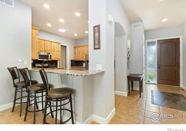 1992 Vineyard Dr, Windsor, CO 80550 - kitchen featuring stainless steel microwave, visible vents, baseboards, and light brown cabinets