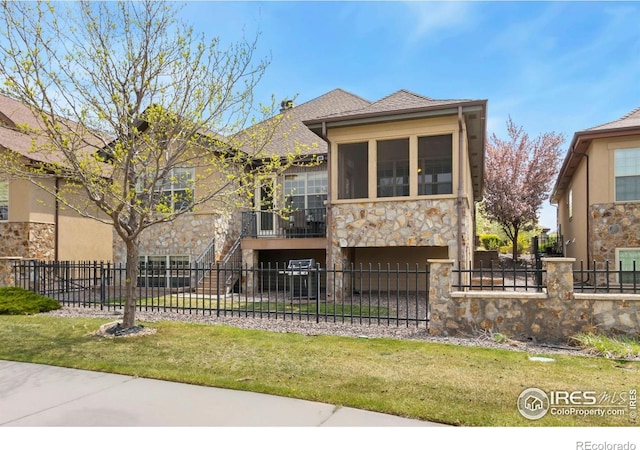 1992 Vineyard Dr, Windsor, CO 80550 - view of front of house featuring a fenced front yard, roof with shingles, and stone siding