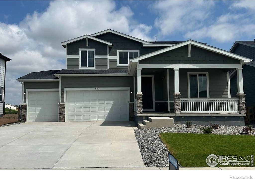 842 Mesic Ln, Windsor, CO 80550 - craftsman house with a porch, concrete driveway, stone siding, and an attached garage