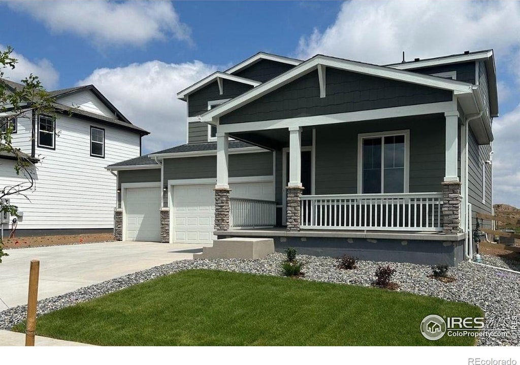 842 Mesic Ln, Windsor, CO 80550 - craftsman-style home with a porch, driveway, a garage, stone siding, and a front lawn