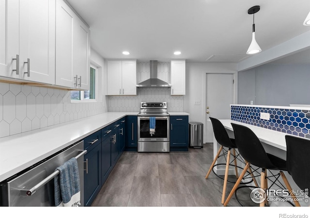 9261 Julian Way, Westminster, CO 80031 - kitchen with light countertops, wall chimney exhaust hood, white cabinets, stainless steel appliances, and blue cabinetry