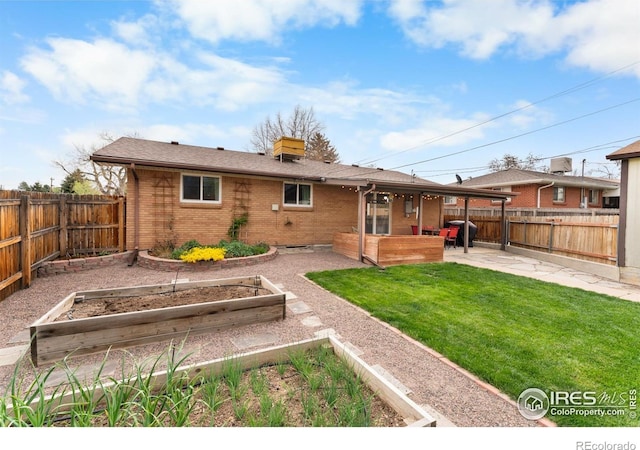9261 Julian Way, Westminster, CO 80031 - rear view of property featuring a garden, a patio area, brick siding, a fenced backyard, and a yard